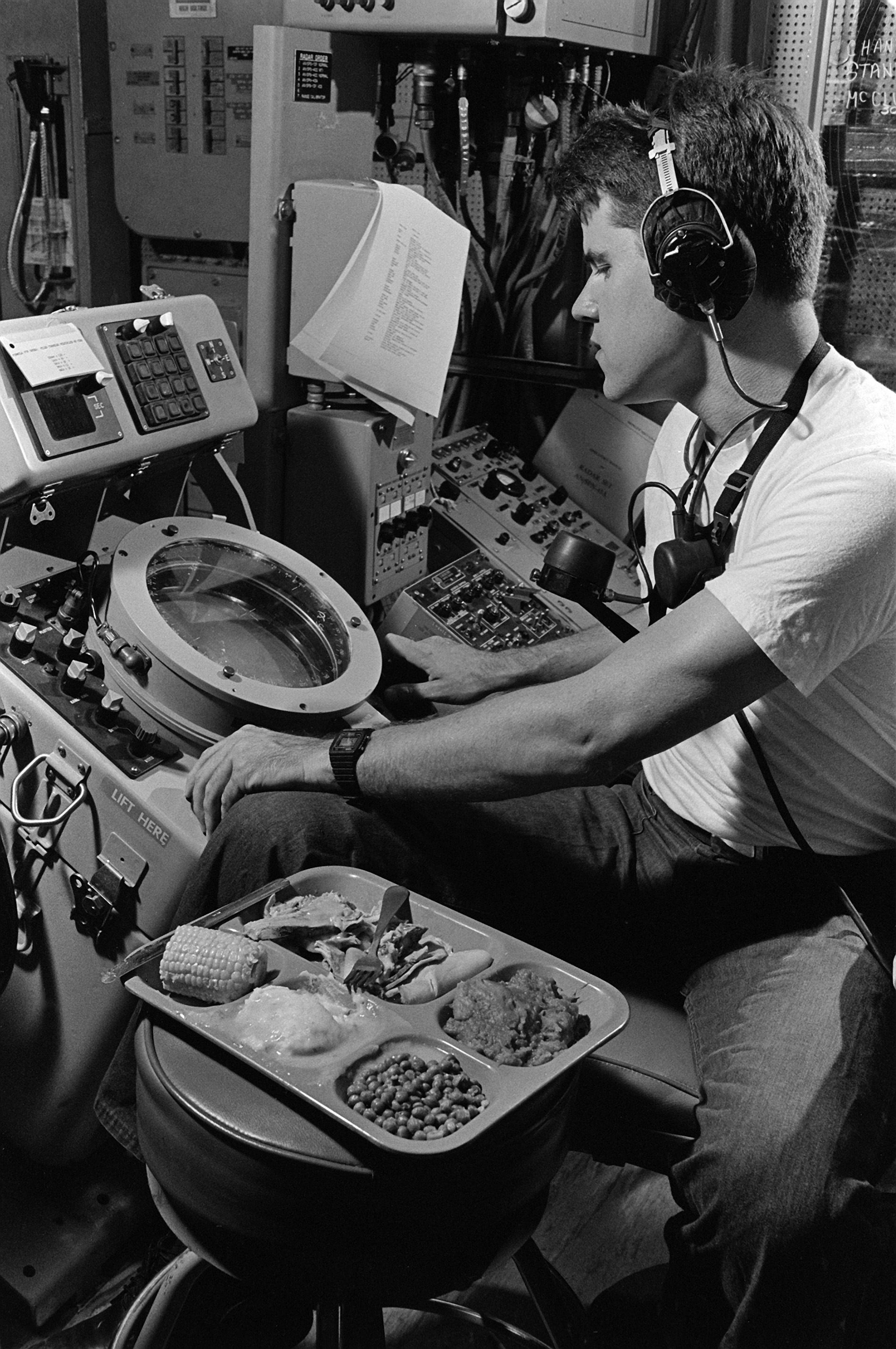 An air controlman airman eats his Thanksgiving dinner while keeping an eye on the radar scope in the helicopter direction center aboard the amphibious assault ship USS OKINAWA (LPH 3), 11/26/1987 DN-SN-88-03255