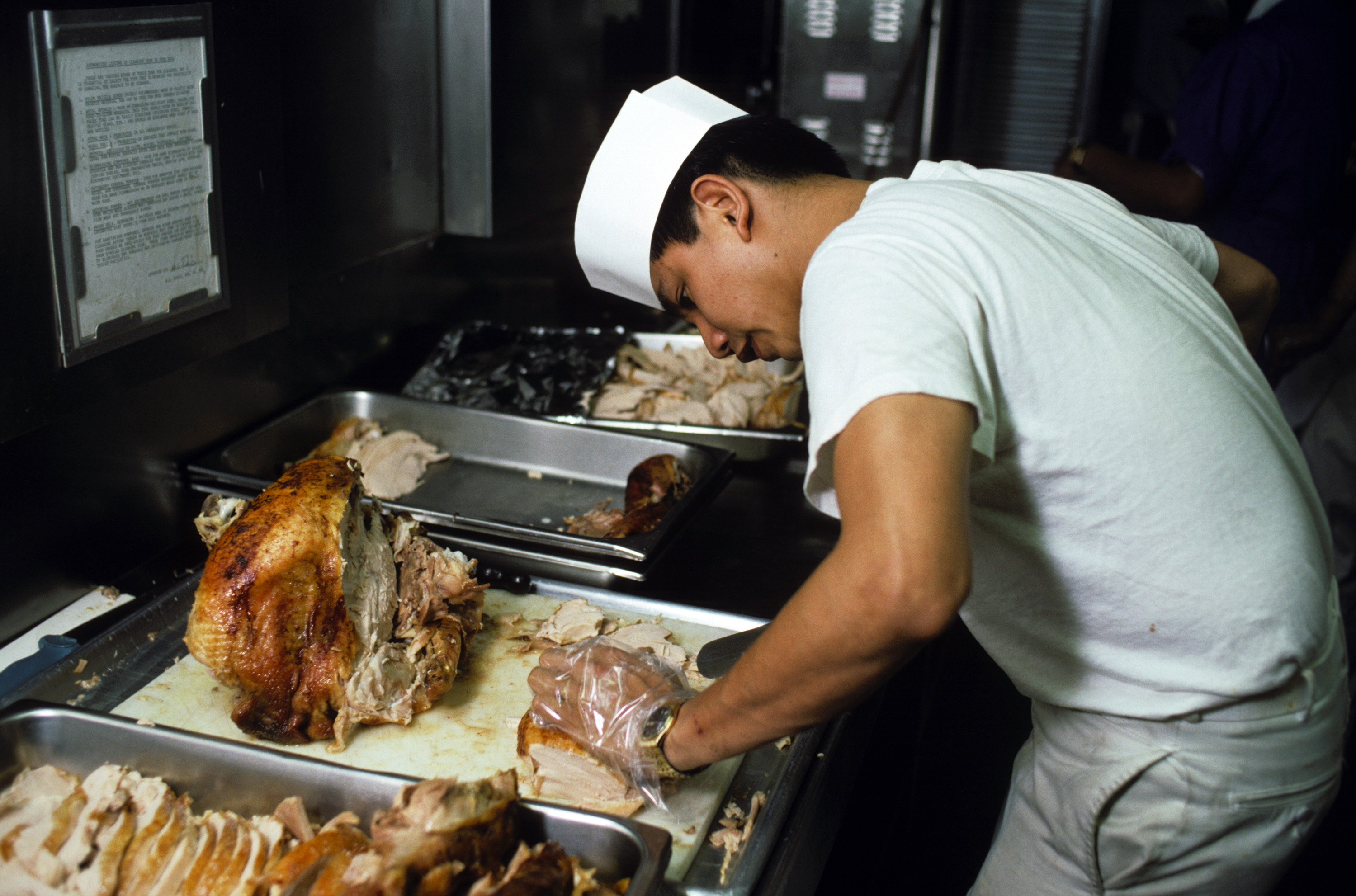 Arabian Sea. A mess management specialist slices a turkey for Thanksgiving dinner aboard the amphibious assault ship USS OKINAWA (LPH 3), 11/26/1987 DN-ST-88-01758